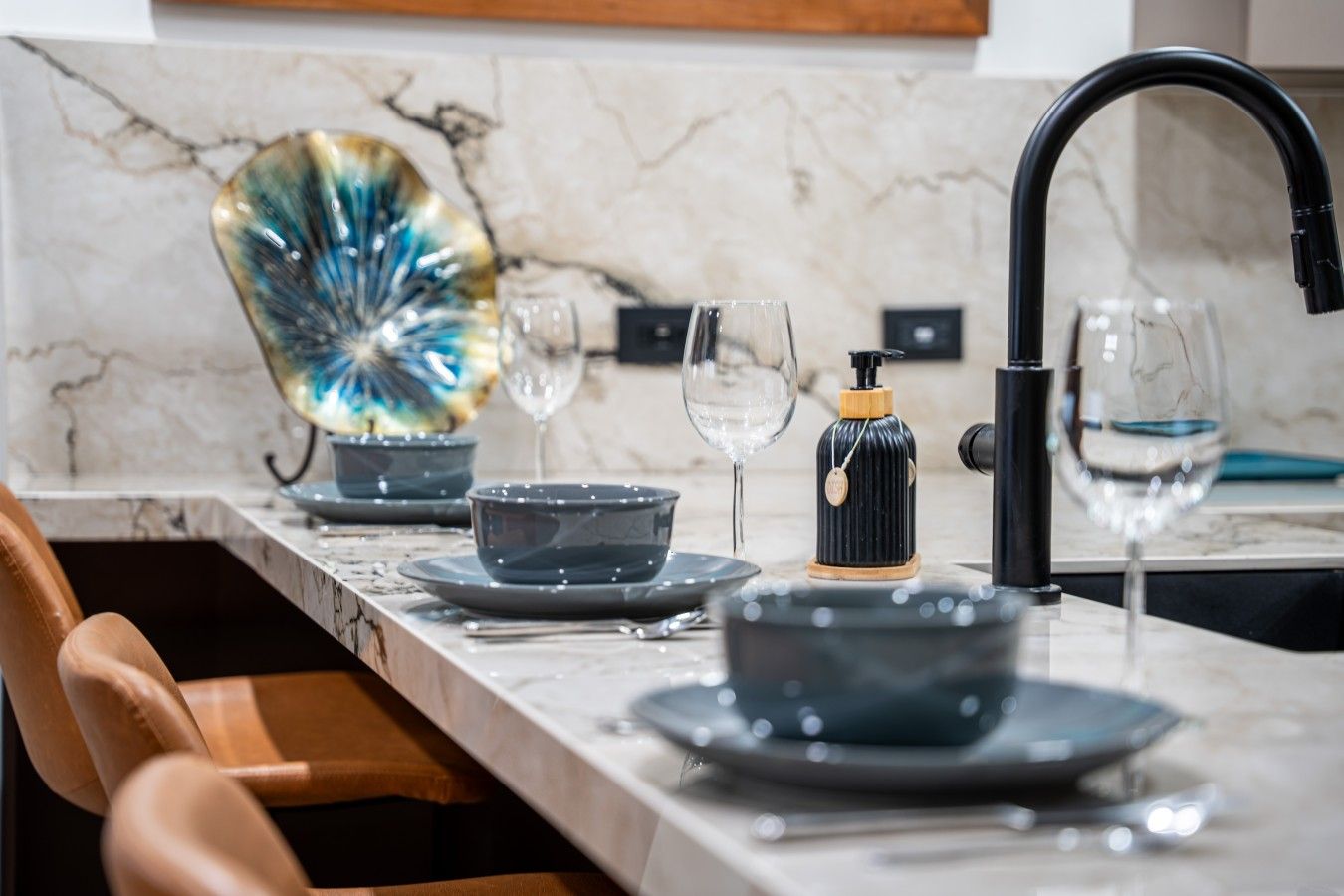 Een moderne keuken met een marmeren aanrechtblad, een zwarte kraan en een decoratief glazen object.