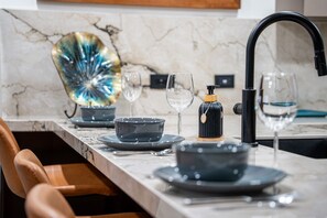 A modern kitchen with a marble countertop, a black faucet, and a decorative glass piece.