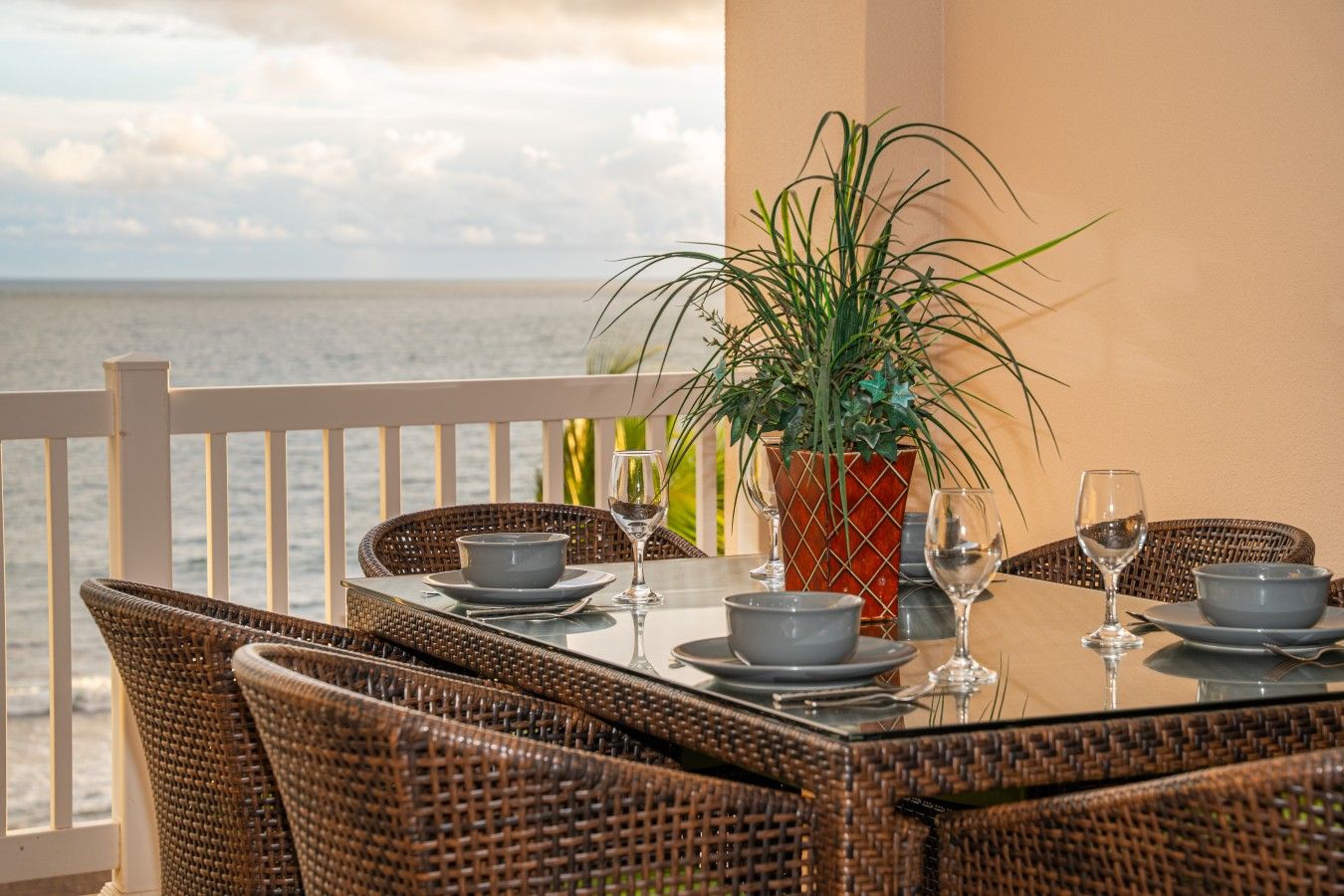 Una mesa de comedor con sillas, una planta en maceta y vista al mar.
