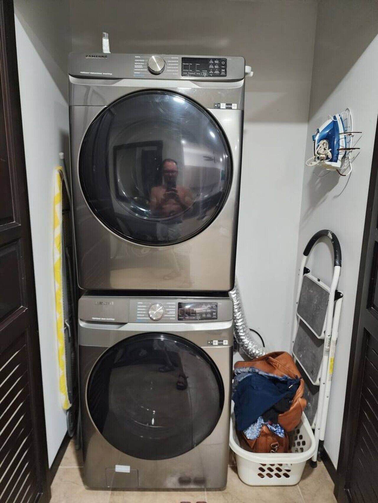 A laundry room with two stacked washing machines and a drying rack.