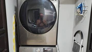 A laundry room with two stacked washing machines and a drying rack.