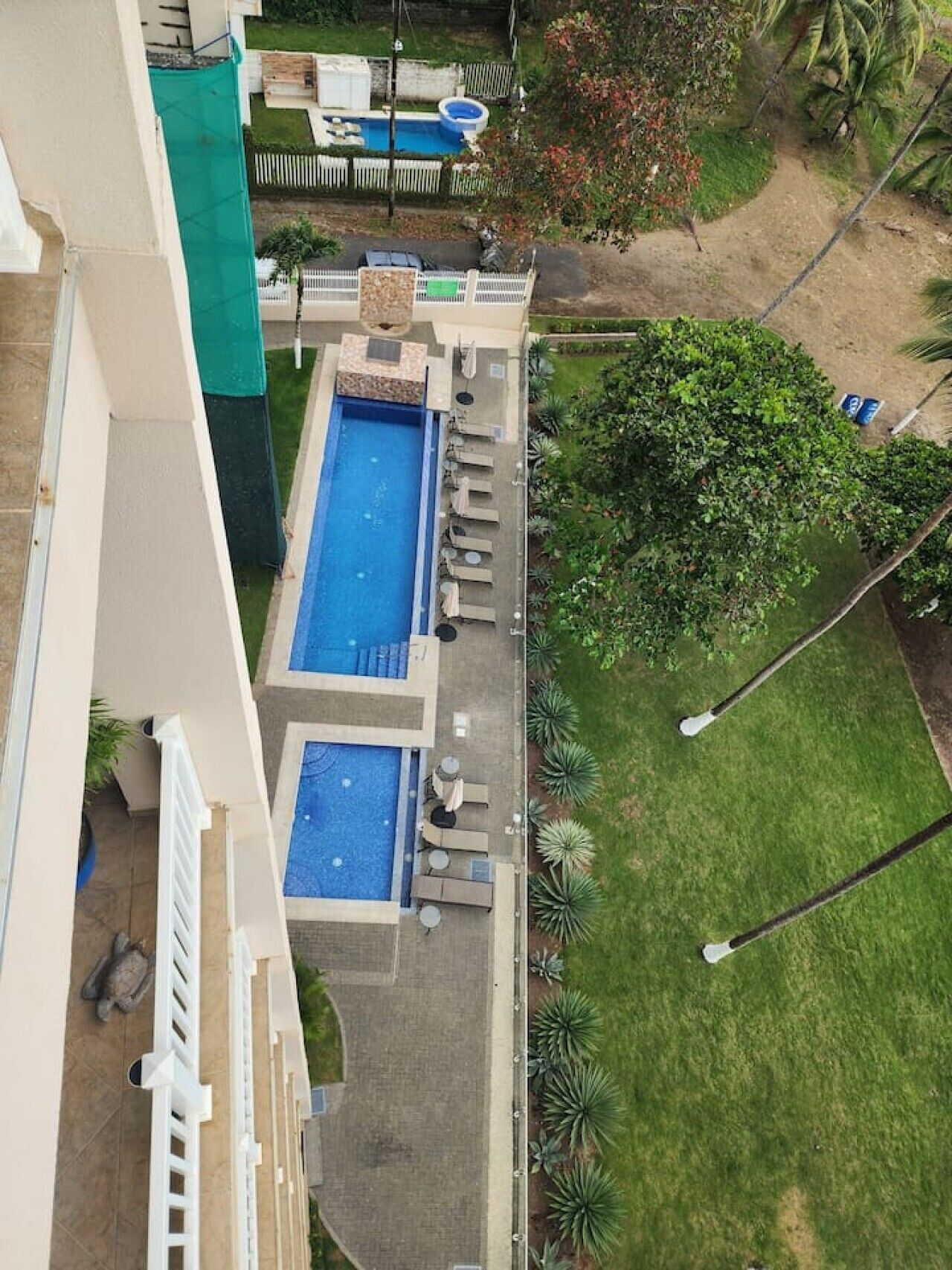 En bostadsfastighet med två swimmingpooler, en uteplats med sittplatser och en välskött gräsmatta.