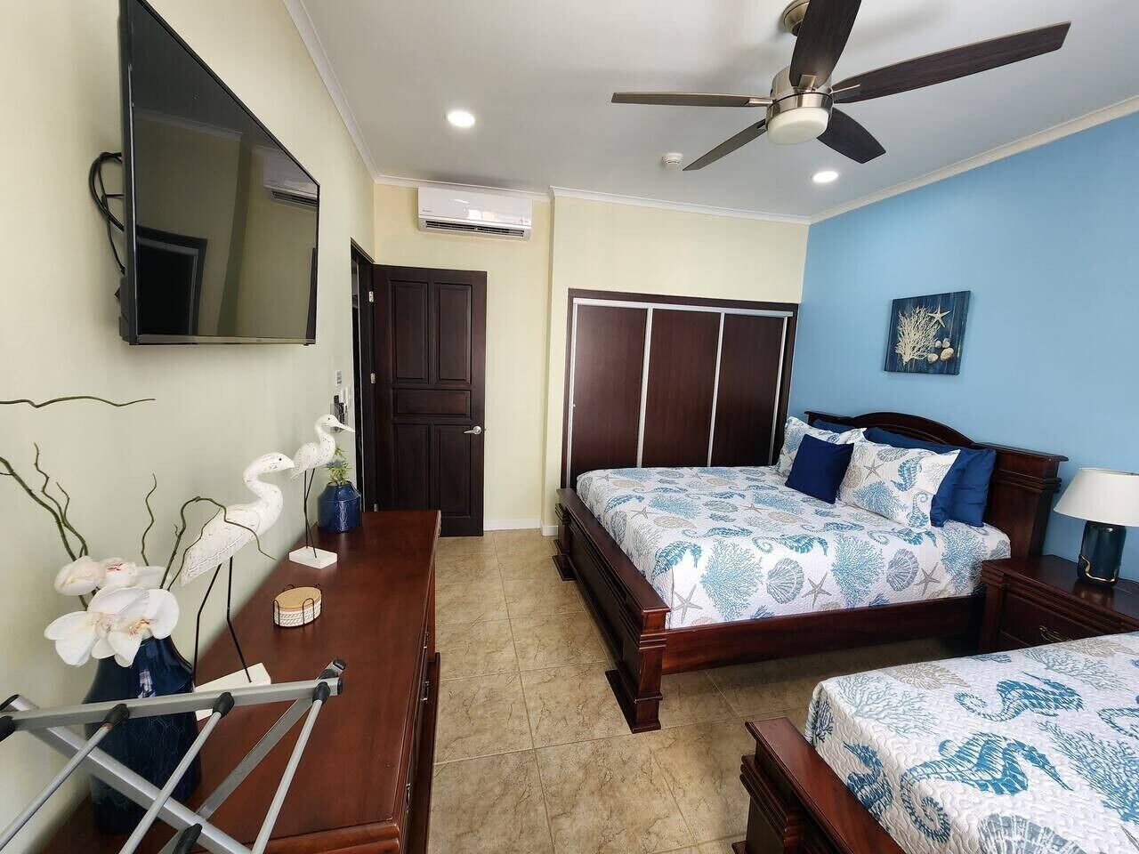 Un dormitorio con cama, escritorio, silla, armario y ventilador de techo.
