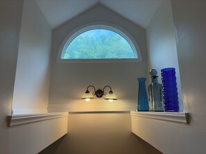 A corner with a white wall, a window with a view of trees, and two wall-mounted lights.