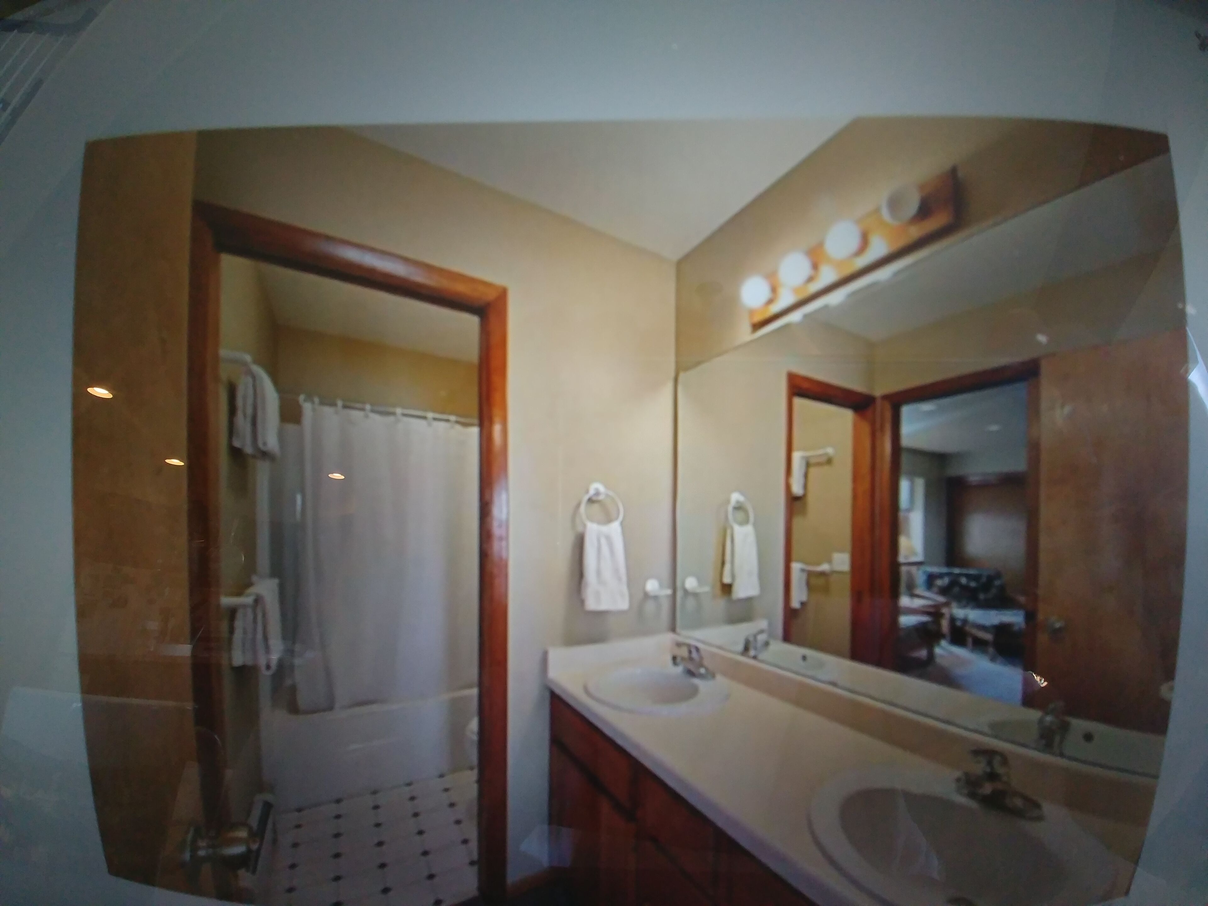 A bathroom with a shower, two sinks, and a large mirror.