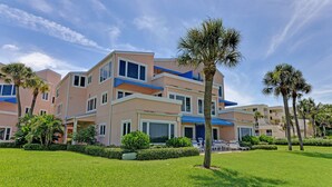 A multi-story hotel with balconies, a well-maintained lawn, and palm trees. - Breathtaking Beach Front Property Ground Floor Condo (Longboat Key)