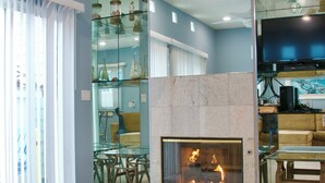Una sala de estar moderna con chimenea de vidrio, televisor y comedor.