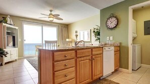 Una cocina con armarios de madera, un lavavajillas blanco y un reloj en la pared.