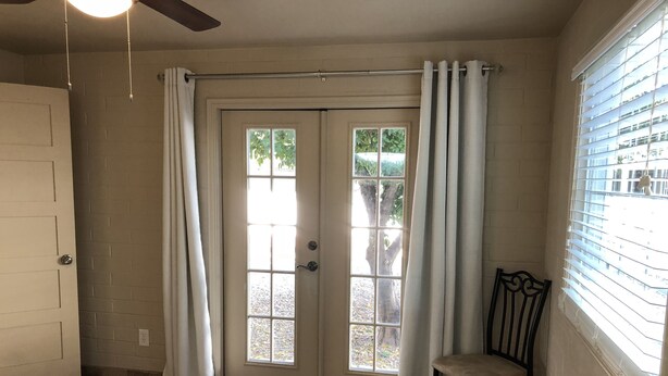 A bedroom with a bed, a chair, a door, and a window with curtains. - Clean, renovated 1 Bedroom with everything you need. Granite, Travertine! (Tucson)