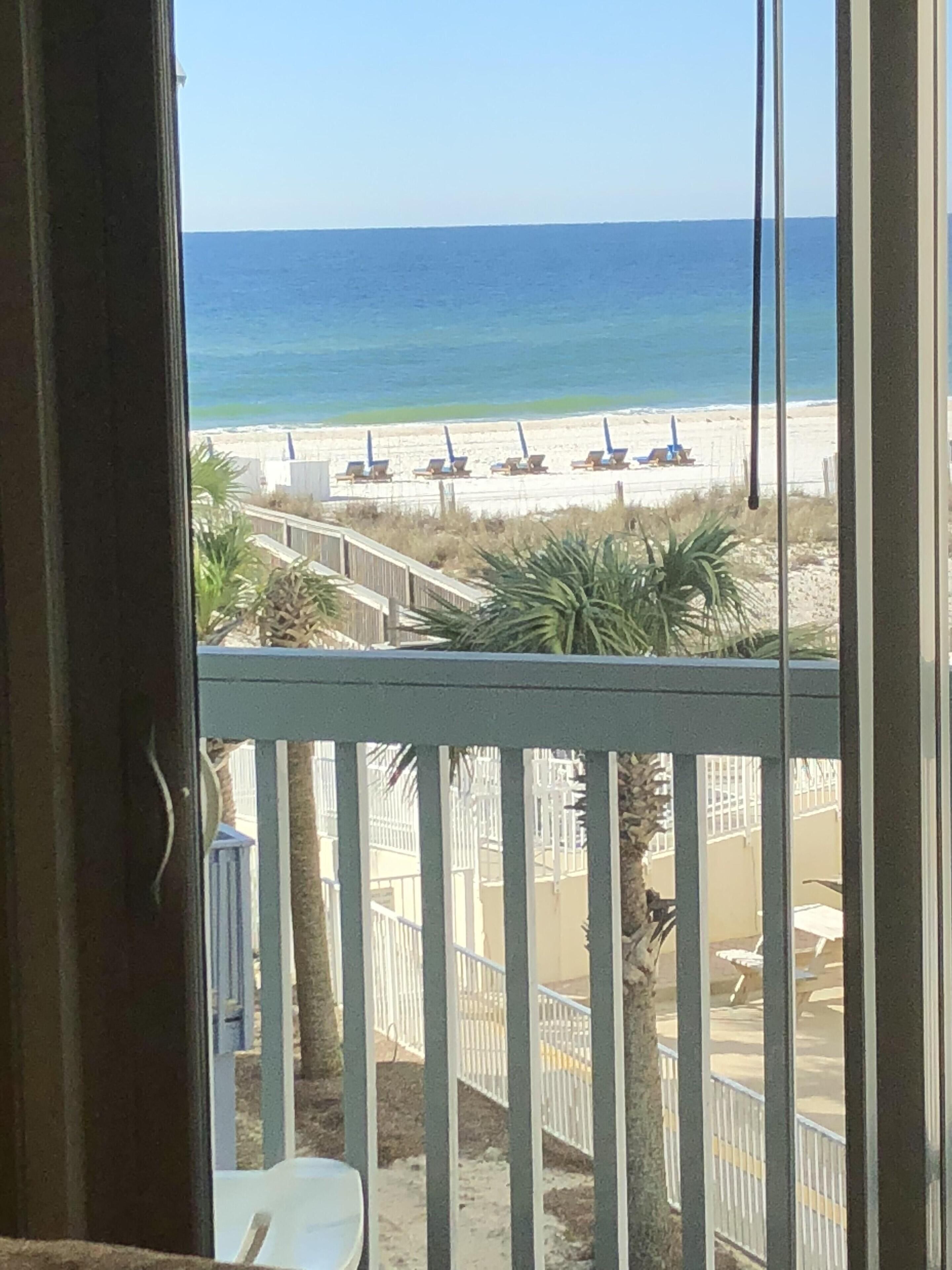 Ein Balkon mit Blick auf einen Strand, Palmen und einen Zaun.