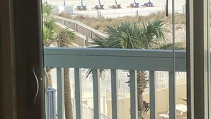Un balcone con vista su una spiaggia, palme e una recinzione.