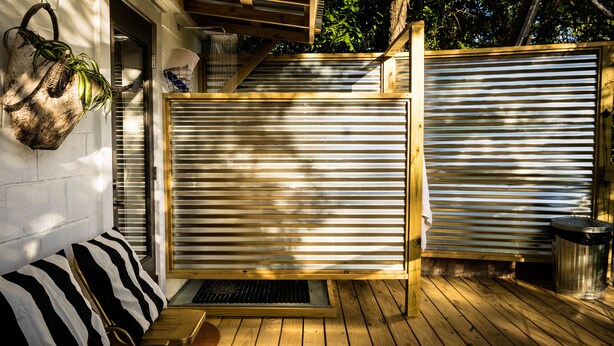 A wooden deck with a metal gate, a bench, and a trash can. - Chic Apartment-Style Suite, Steps From Main, Luxury Finishings, Outdoor Shower (Fredericksburg)