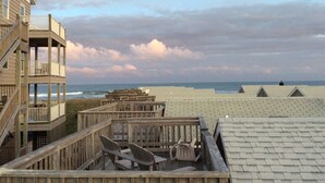 Eine Holterrasse mit Stühlen und einer Holzkonstruktion mit Geländern, die auf einen Strand blickt.