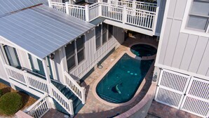 Et toetagers hus med swimmingpool, overdækket terrasse og hegnede træterrasse.