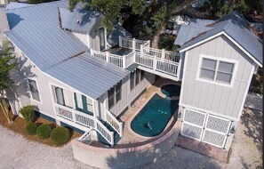 Una casa de dos pisos con piscina, terraza y zona cercada.