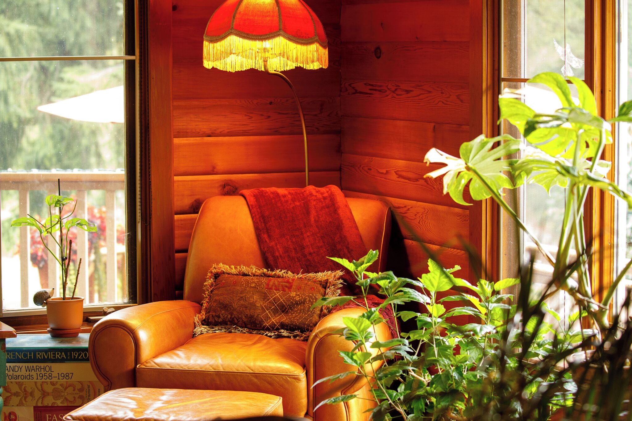A cozy room with a leather armchair, a red throw blanket, and a hanging lamp.