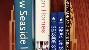 A bookshelf with books titled 'New Seaside Interiors', 'Vacation Homes', 'Seaside Style Vol. II', and 'Portside and Home Memories'.