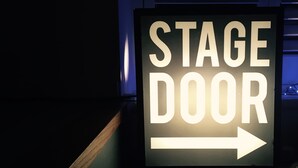 A sign with "STAGE DOOR" and an arrow pointing to the right.