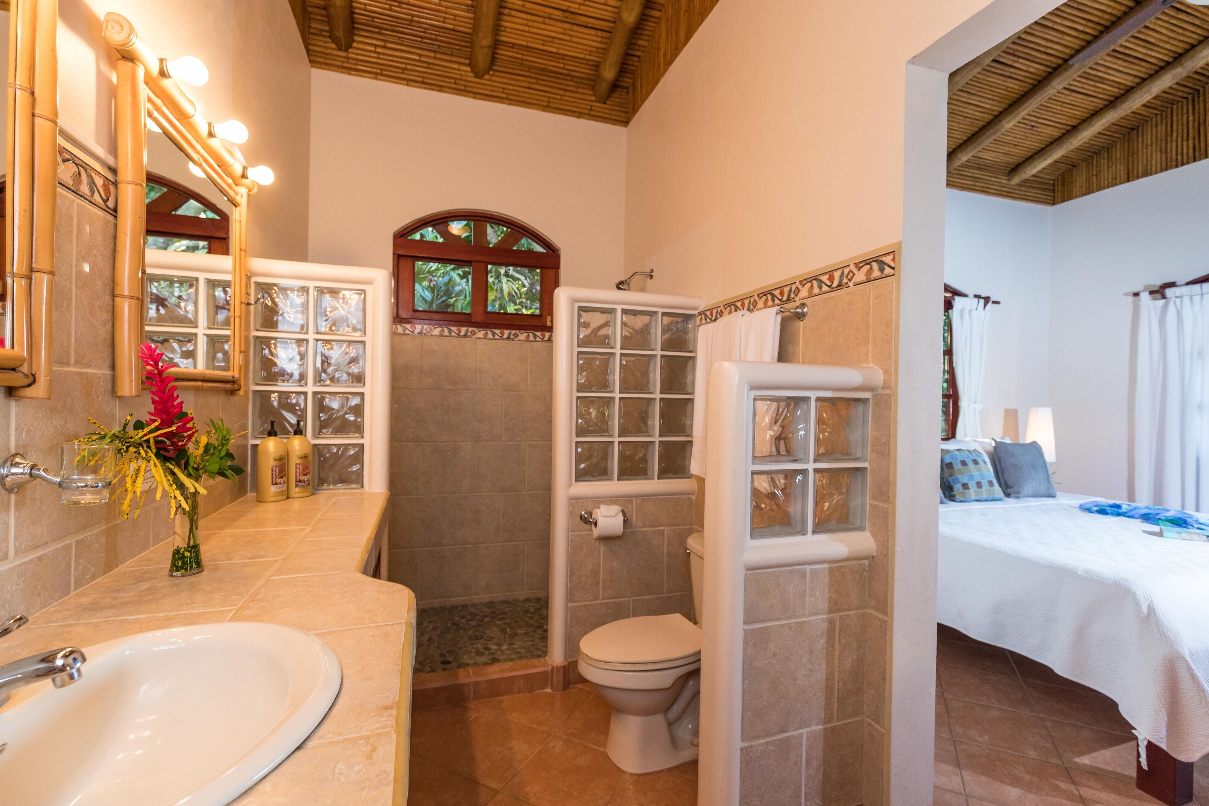 A bathroom with a sink, toilet, shower, and a glass-enclosed shower area.