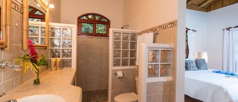 A bathroom with a sink, toilet, shower, and a glass-enclosed shower area.