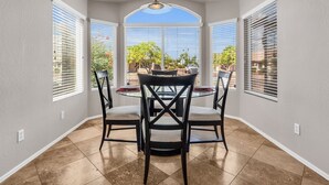 A dining area with a round table and four chairs, large windows with blinds, and a view of the outdoors. - Old Town Scottsdale oasis with resort style back yard!!! (Scottsdale)