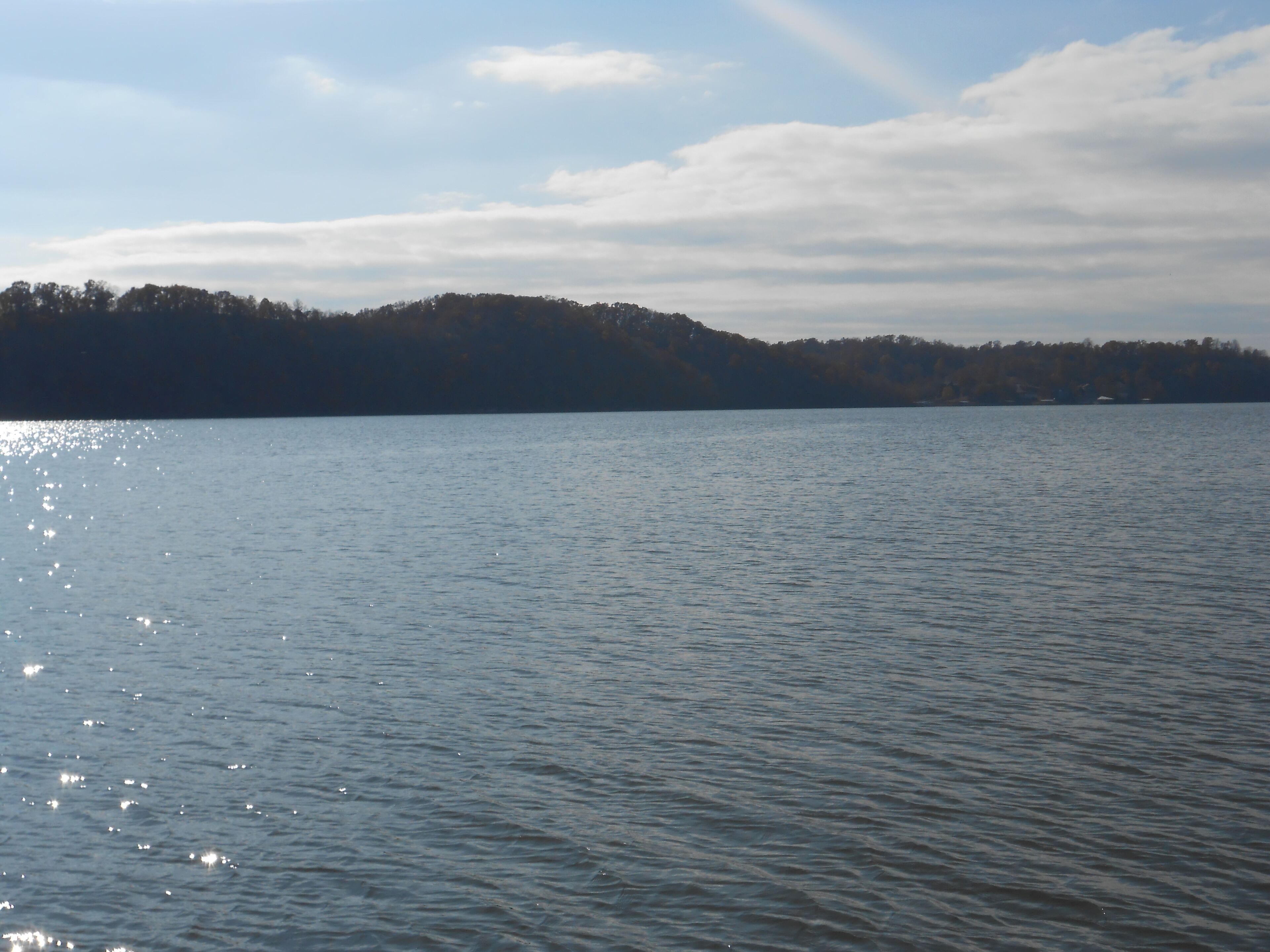 A calm lake with a forested hill in the background.