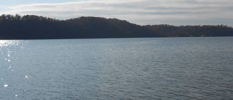 A calm lake with a forested hill in the background.