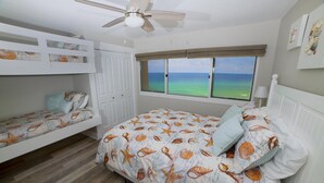 Un dormitorio con vista al océano, literas y un ventilador de techo.