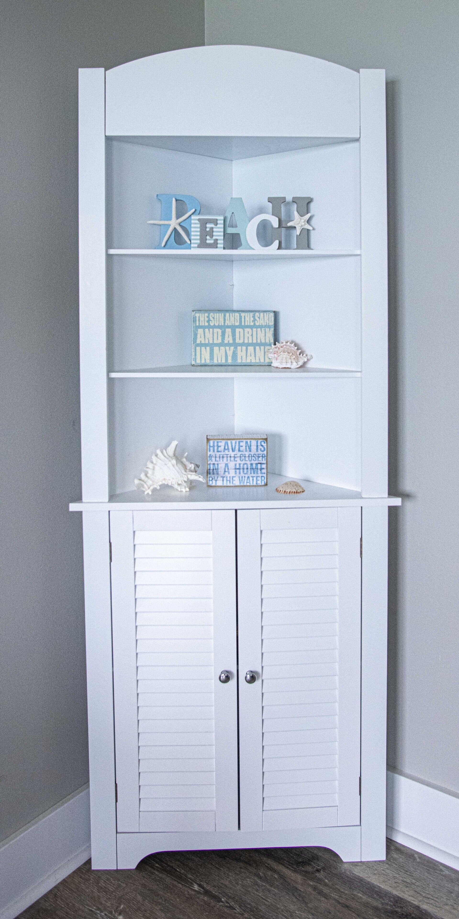 Un mueble blanco con estantes y una puerta, que contiene objetos decorativos y carteles.