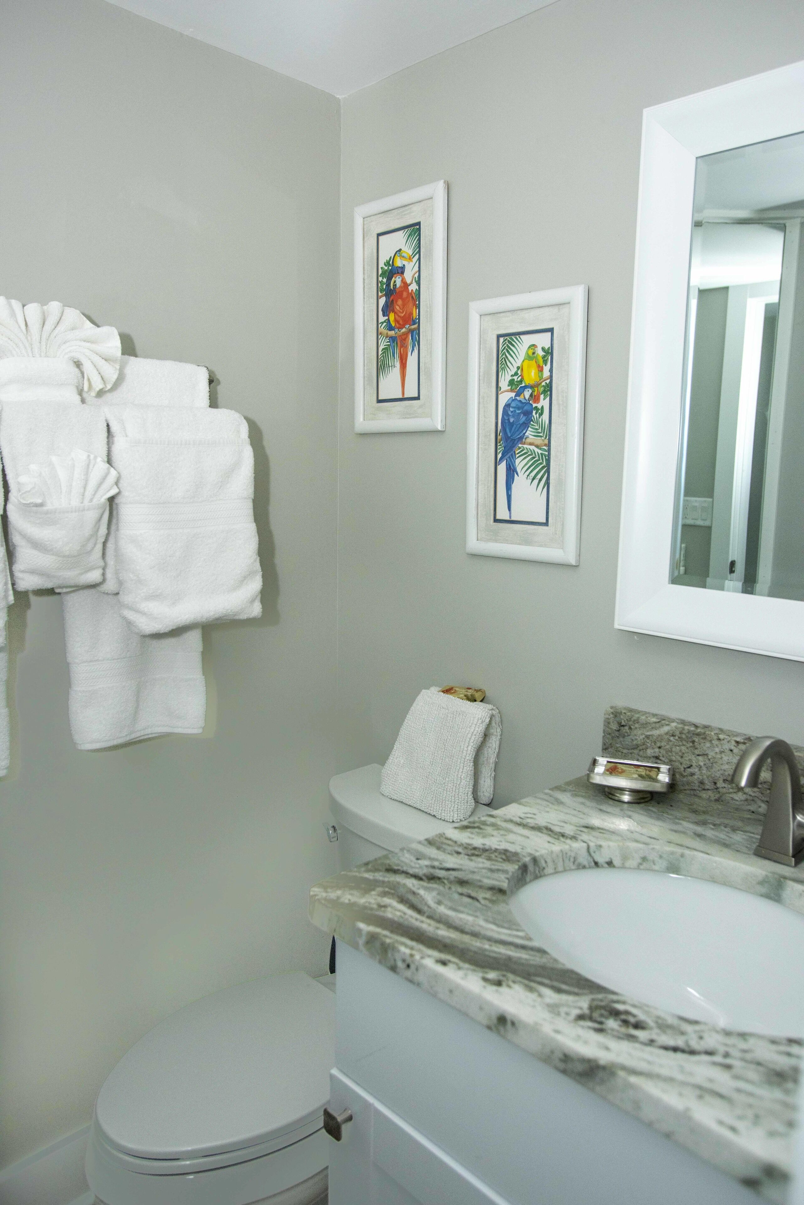 Un baño con inodoro, lavamanos y perchero para toallas.