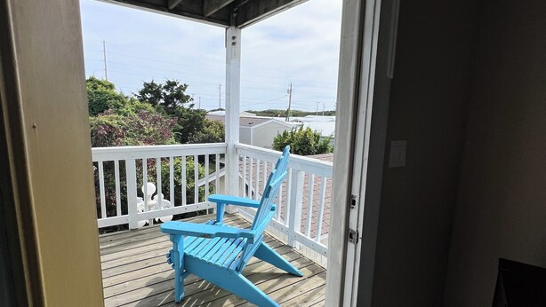 A wooden deck with a blue chair and a white railing.