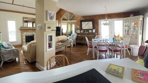A spacious living area with a dining table, chairs, and a kitchen in the background.