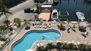 A swimming pool with lounge chairs and umbrellas, surrounded by palm trees and a marina with boats. - Luxury Condominium In Key Largo... Sunsets, Marina (Key Largo)