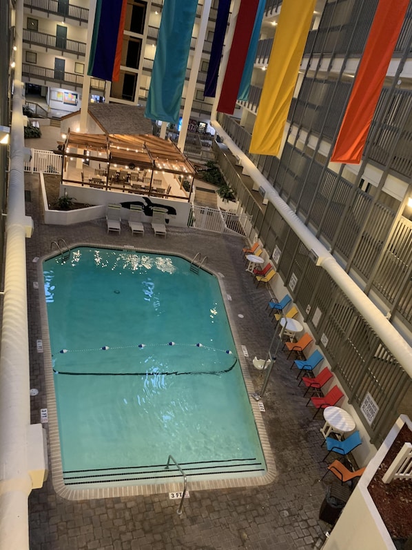 Una piscina interior con solárium de baldosas, sillones de descanso y una zona de estar cubierta.