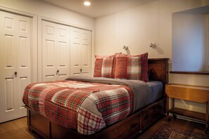 A bedroom with a wooden bed, a nightstand, a mirror, and a door.