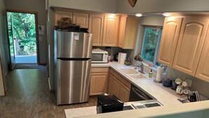 A modern kitchen with stainless steel appliances, wooden cabinets, and a large window providing natural light. - Unique Home in Willard, Wa. 40 acres, 50 feet from Little White Salmon River (Willard)