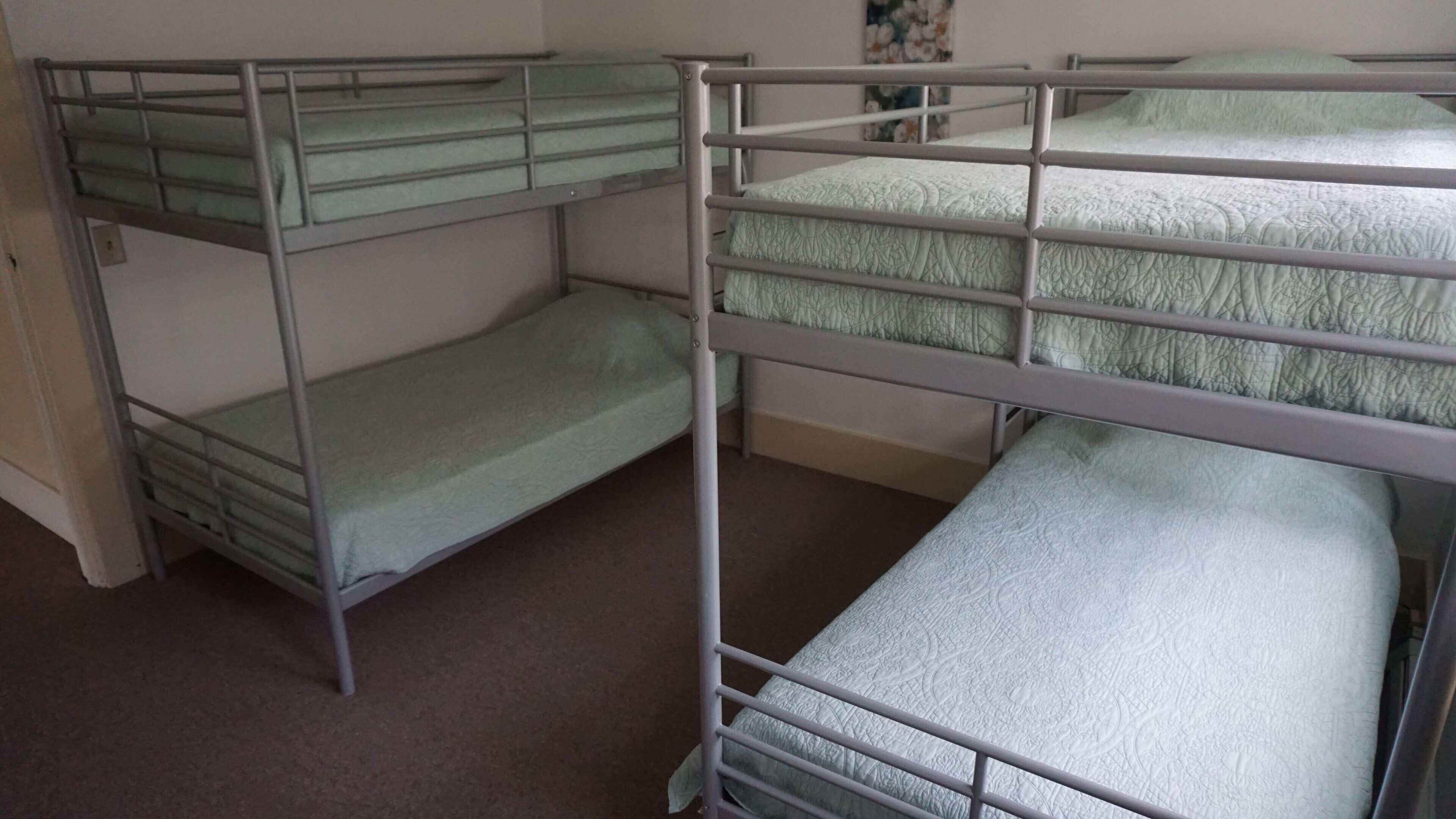 Ein Schlafsaalzimmer mit Etagenbetten, Teppichboden und einer schlichten Wand.