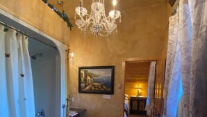 A bathroom with a bathtub, shower, and a chandelier.