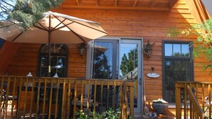 A wooden cabin with a balcony, a front door, and a staircase leading to the entrance.