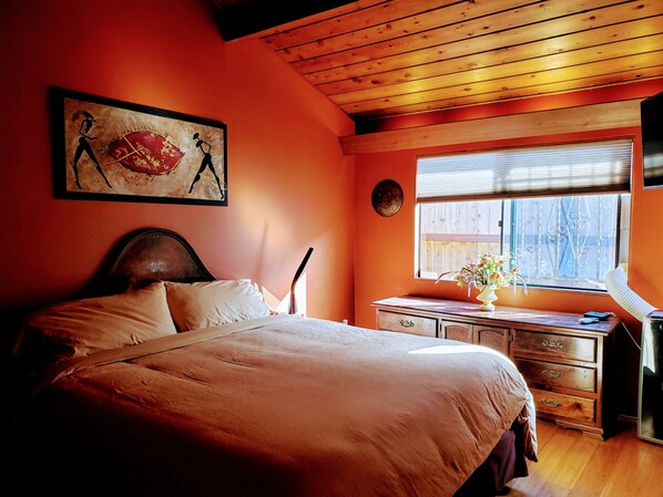 A bedroom with a bed, wooden headboard, a dresser, a window with blinds, and a painting on the wall. - Beautiful Oceanfront Home, Gorgeous Views, Deck and Patio! Best Value! (Encinitas)