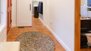 A hallway with a patterned rug, a door, and a wall-mounted towel rack. - Streamside Cottage Half Mile to Town of Woodstock (Woodstock)