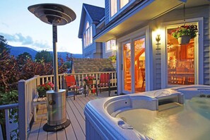 Relax and unwind on the outdoor deck, featuring a hot tub, comfortable seating, and a scenic mountain view.