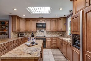 A spacious kitchen with wooden cabinets, a central island, a microwave, and a dishwasher. - Luxury home just blocks from the magnificent El Paseo shops and restaurants (Palm Desert)