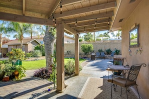 An outdoor patio area with a covered seating area, a table, and chairs. - Luxury home just blocks from the magnificent El Paseo shops and restaurants (Palm Desert)