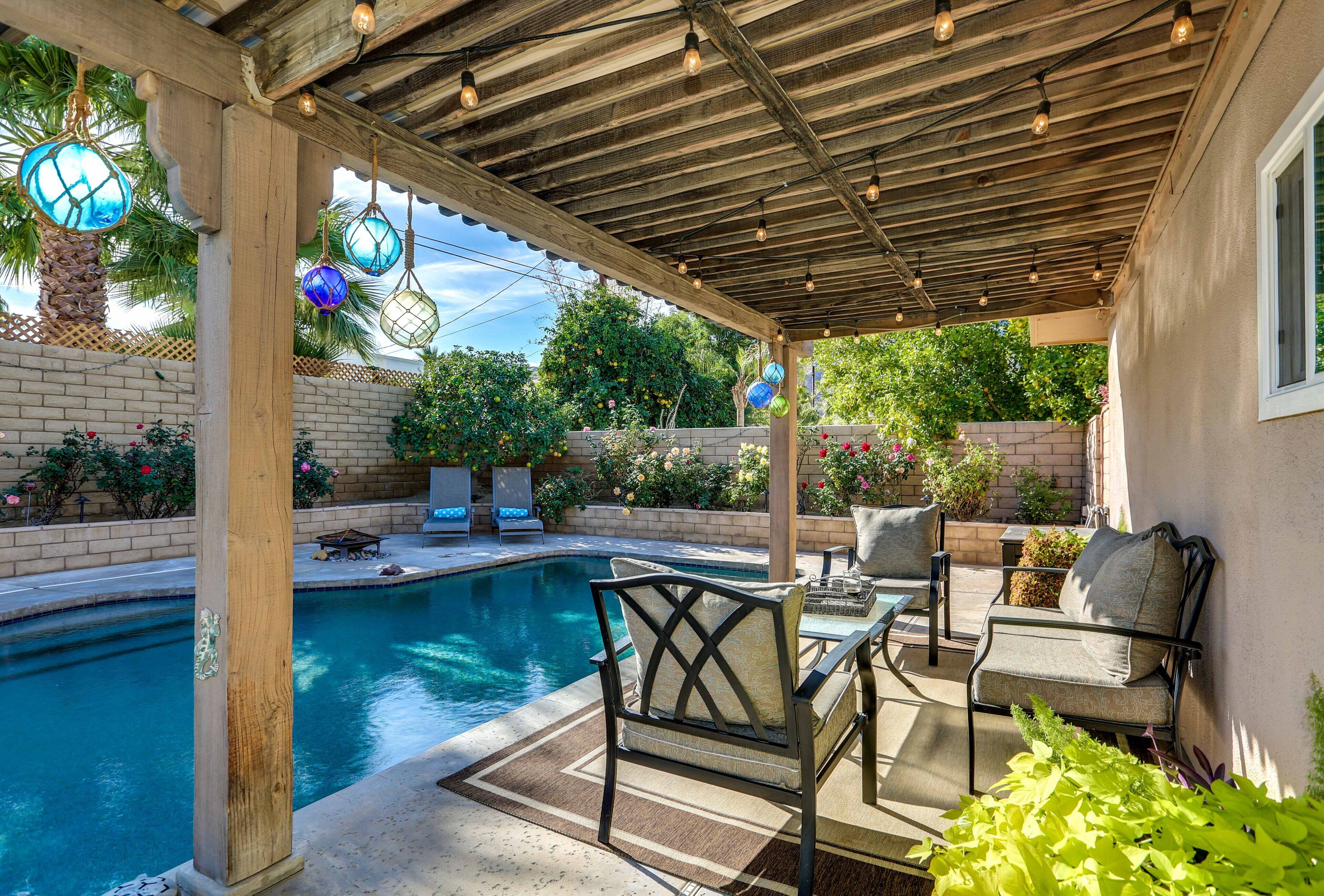 A covered outdoor area with a pool, seating, and decorative lighting.