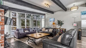 A spacious living area with large windows, a fireplace, and a modern kitchen. - Mountain View Blue Mountain (Blue Mountains)