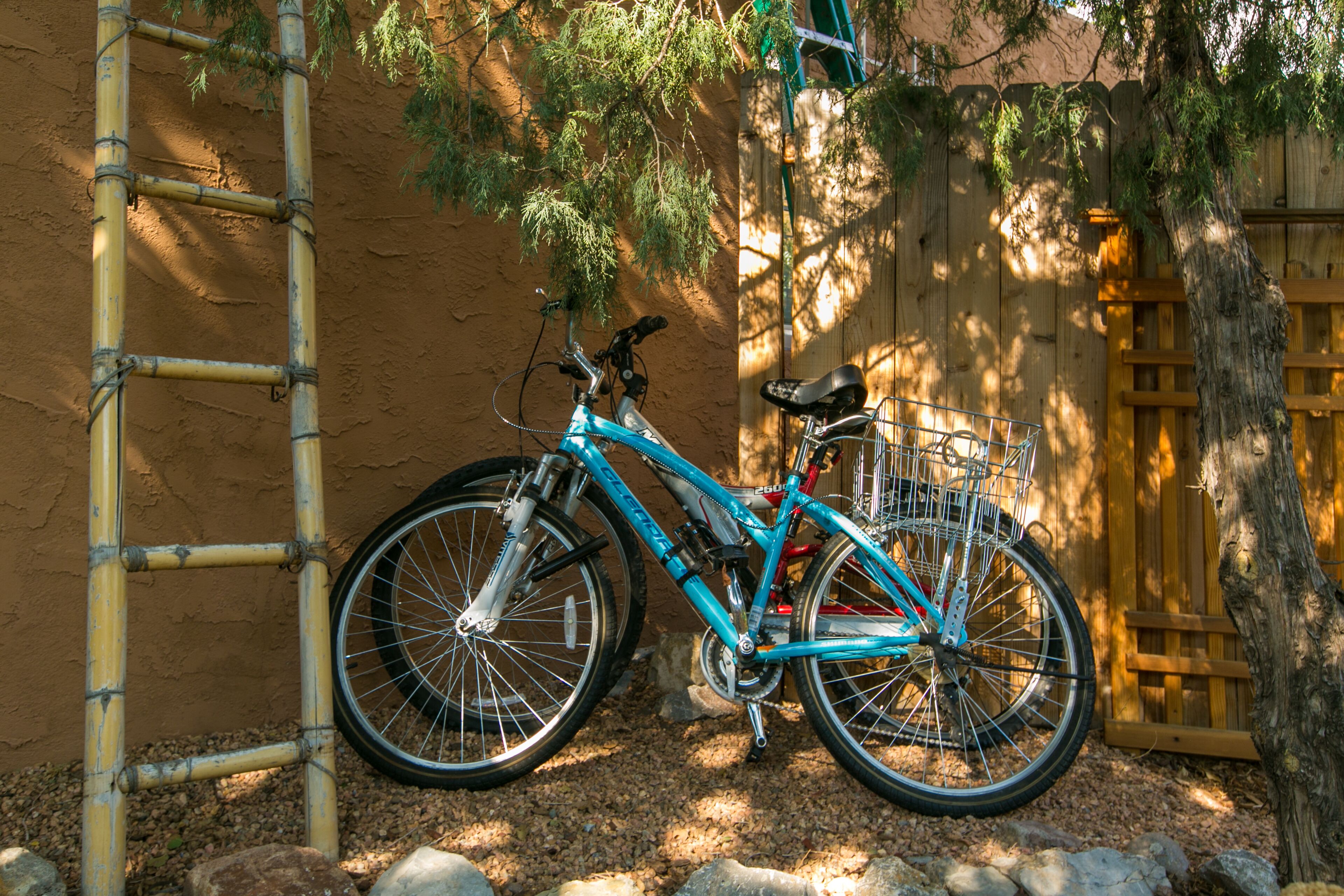 Un vélo bleu avec un panier, appuyé contre un échafaudage en bambou et une clôture en bois.