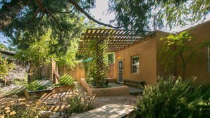 Un espace extérieur aménagé avec une terrasse en bois, une pergola et diverses plantes.