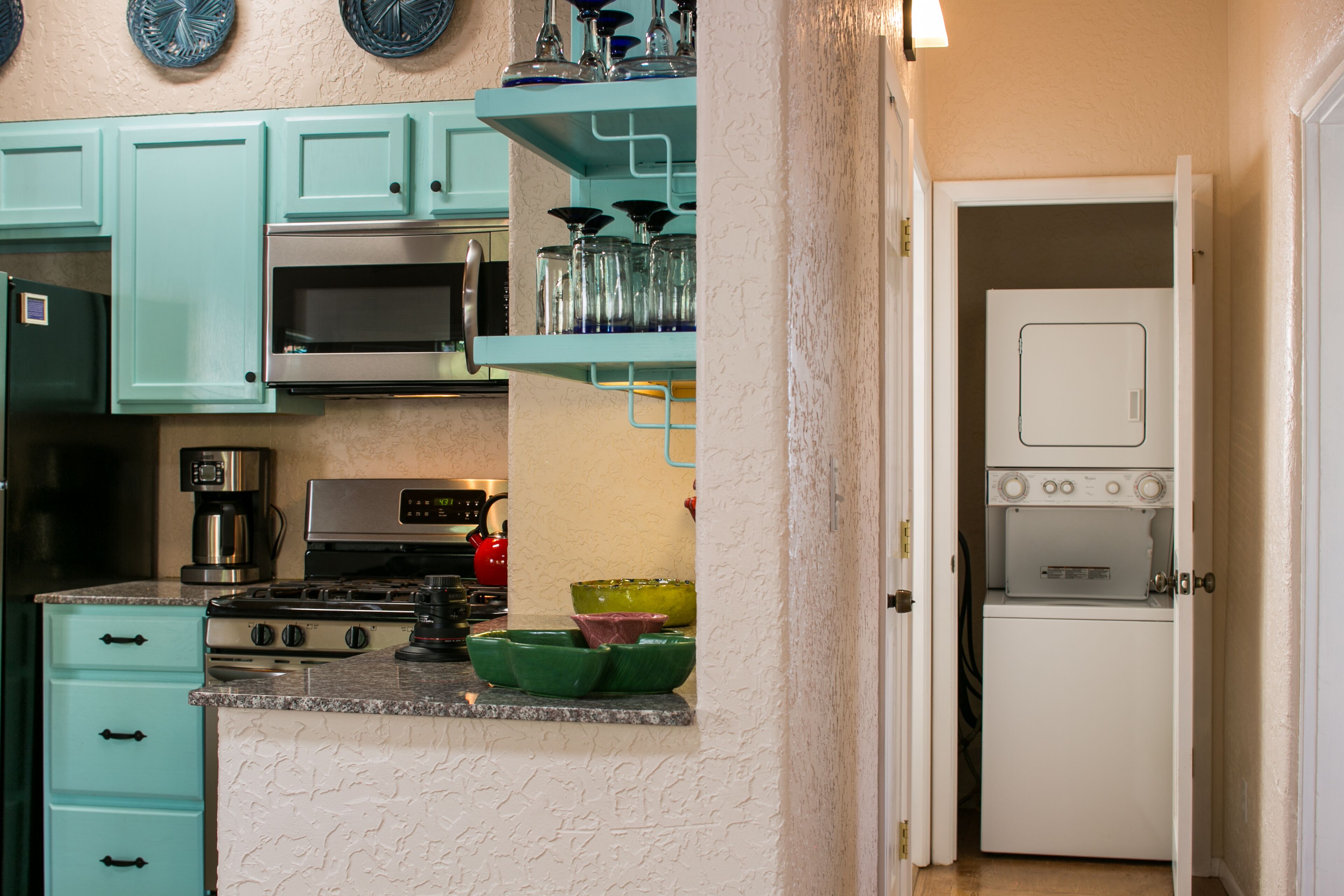 A kitchen with teal cabinets, a microwave, a stove, and a refrigerator.