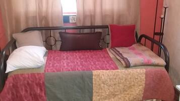 Un lit avec un cadre en métal, une couette et deux oreillers.
